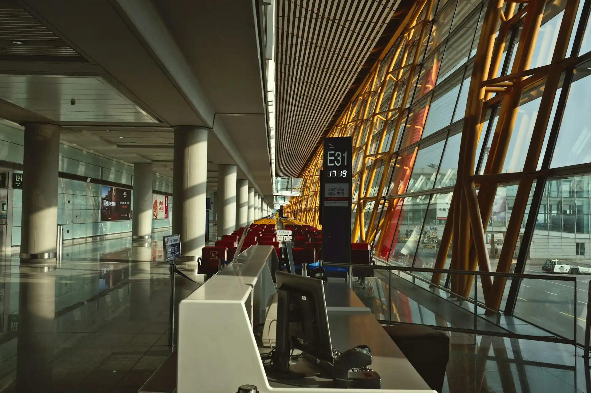 Spacious modern airport terminal interior with glass ceiling and travellers walking through